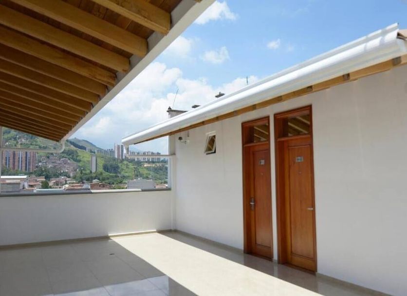 Hotel Monarca in Itagüí: rooftop terrace with mountain and city view, white walls and wooden doors