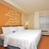 Fairfield Inn and Suites by Marriott Williamsport room with king bed, TV, window and orange accent wall