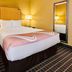 Quality Inn & Suites Westminster Seal Beach room with king bed, lamps and floor mirror in Westminster