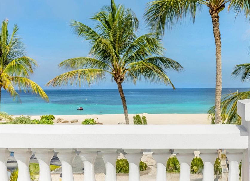 Amsterdam Manor Beach Resort in Noord with palm-framed ocean view and white balcony railing