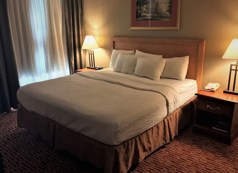 Host Inn an All Suites Hotel in Wilkes-Barre guest room with king bed, bedside lamps, and window light