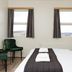 Guesthouse Brekka in Husavik guest room with twin windows, bed, and green chairs