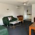 Armidale Pines Motel in Armidale, lounge with green sofa, coffee table, desk and kitchenette doorway