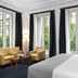 Melia Paris Champs Elysees room in Paris with king bed, armchairs and tall windows with French balcony view