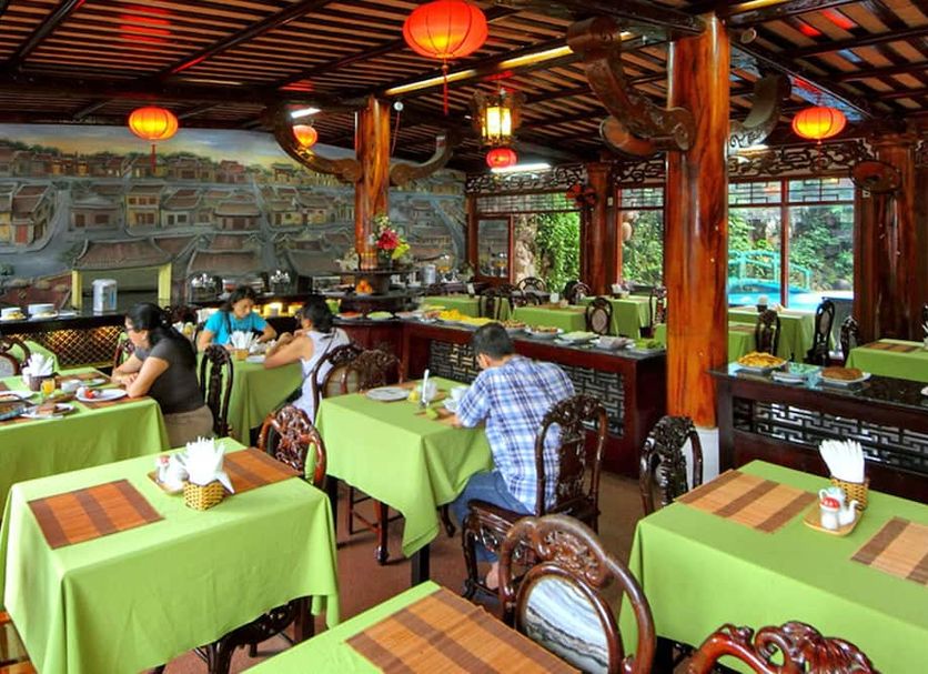 Thanh Binh 2 Hotel in Hoi An restaurant with green tablecloths, carved chairs and red lanterns