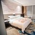 Zhongyuan Hotel in Anyang guest room with king bed, wall-mounted TV, desk and seating area