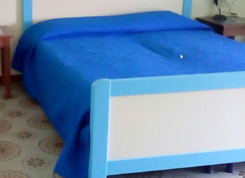 B&b La Scogliera in Le Castella, blue bedspread on a blue-framed bed in a simple guest room
