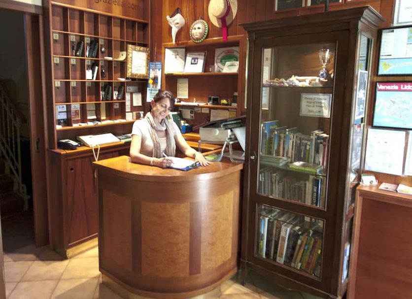 Antica Villa Graziella in Venice reception desk with wooden shelving and display cabinet