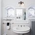 Stewart Inn Wausau bathroom with pedestal sink, ornate mirrors, wall sconce, and gray radiator