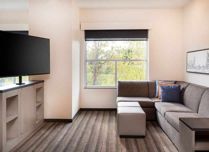 Hyatt House Nashville Airport room with sectional sofa, TV, window view, and ottoman in Nashville