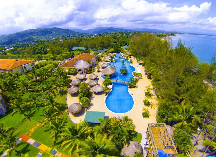 La Ensenada Beach Resort in Tela with oceanfront pools, lush gardens, and hillside coastal views