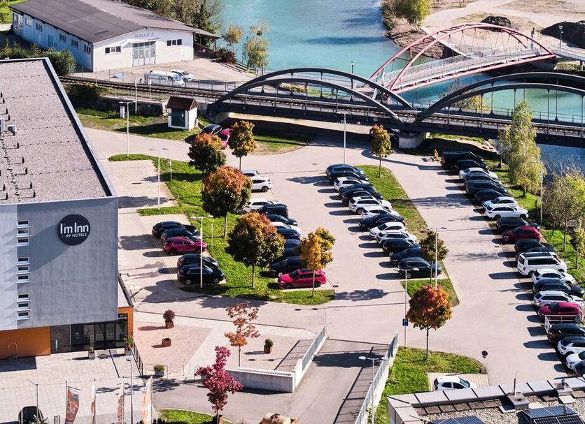 I’m Inn Wieselburg hotel exterior with parking lot beside a river and arched bridge