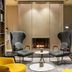 Holmes Hotel London lounge with fireplace, two gray chairs, yellow accent chairs and bookshelves in London