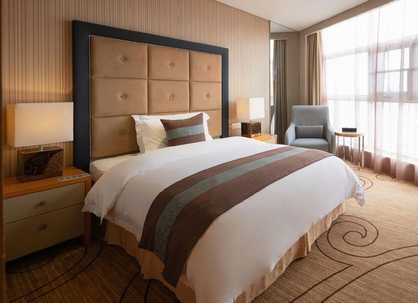 Xinhua Jianguo Hotel in Jiujiang guest room with king bed, armchair, and large window