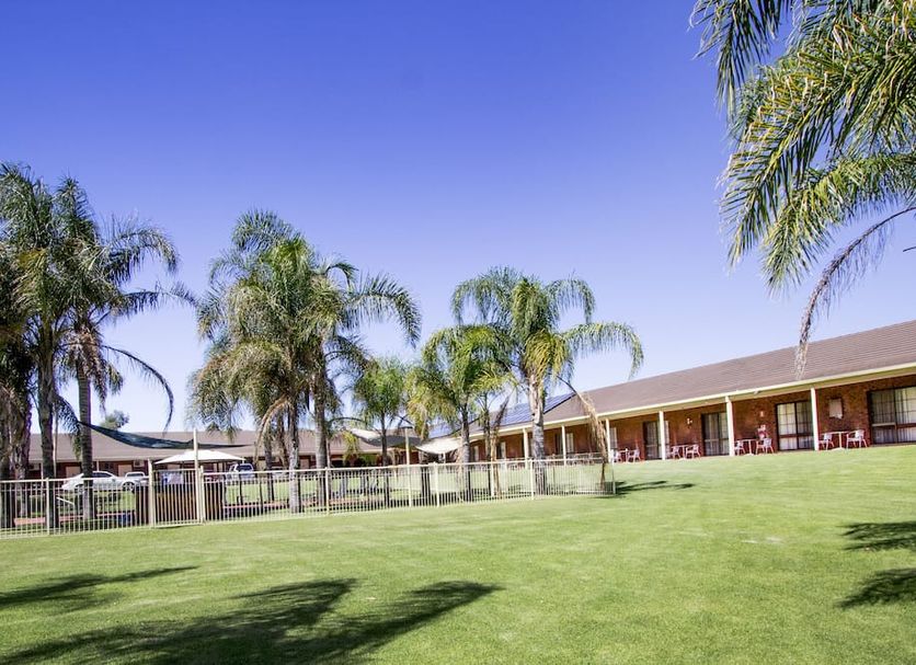 Tocumwal Golf Resort in Tocumwal with palm trees and a wide green lawn beside the building