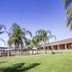 Tocumwal Golf Resort in Tocumwal with palm trees and a wide green lawn beside the building