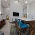 Hampton Inn & Suites Orlando-International Dr. North lounge with high-top table, blue stools and wall TV