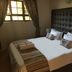 House on York in Johannesburg: a bedroom with a tufted headboard, bedside lamp, window and neatly made bed.