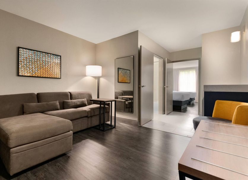 La Quinta Inn & Suites by Wyndham Montgomery room with sectional sofa, lamp, mirror and bed in back hallway