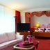 Eden Hotel Bad Krozingen room with red canopy bed, sofa, TV and large window