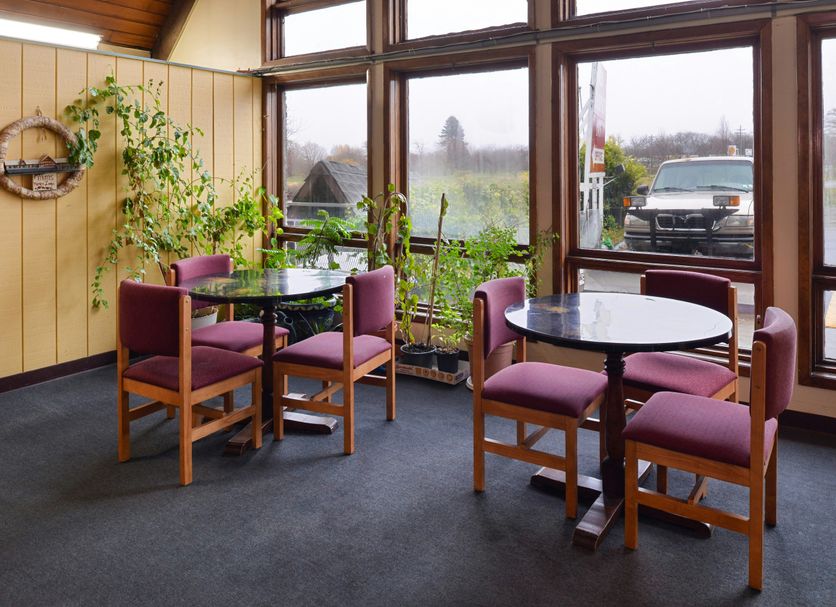 Red Carpet Inn North East lounge with round tables, purple chairs, and large windows overlooking a parking lot.