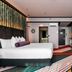 Naumi Hotel Wellington guest room with a large bed, colorful striped floor, and open bathroom area