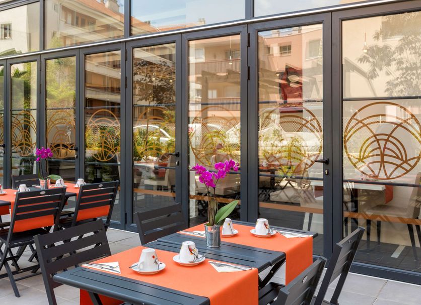 Outdoor terrace at Best Western Hotel Journel Saint-Laurent-du-Var with tables, chairs and glass doors