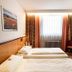 Hotel St. Pierre in Bad Hönningen guest room with two single beds, window, curtains, and chair