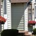 The Beach House in Mackinaw City with a cottage-style exterior, flower boxes, and a beach view