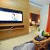 Meshal Hotel & Spa in Manama guest room with wall-mounted TV, armchair, and orange curtains