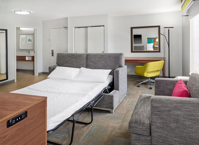 Hampton Inn Kansas City The Legends guest room with sofa, desk chair, and wall mirror in Kansas City