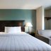 Copley Inn & Suites By OYO Akron Oh guest room with king bed, lamps, and seating area in Copley