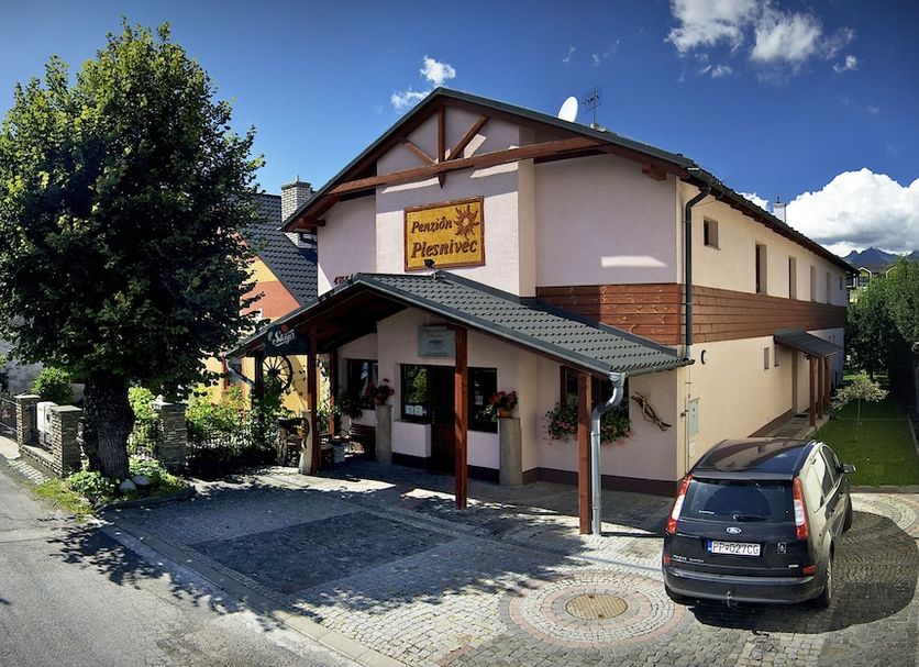 Penzion Plesnivec in Poprad, street view of the guesthouse entrance with parked car and tree