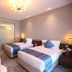 Vip Hotel in Doha guest room with two twin beds, chandelier lighting, and an accent chair