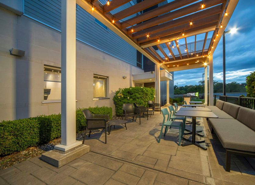 Home2 Suites by Hilton Saratoga Malta patio with covered seating and outdoor dining area at dusk