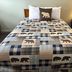 White Mountain Motel And Cottages in Lincoln, bed with bear-pattern quilt and lamp on bedside table