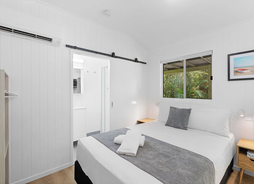 Kipara Tropical Rainforest Retreat in Airlie Beach bedroom with king bed, window view and white decor