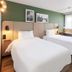 Campanile Nature - Mont De Marsan room with two twin beds, wood accents, and a large window in Mont-de-Marsan