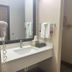 Hotel Piney Woods Huntsville bathroom vanity with sink, mirror, towels, and wood door