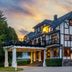 Hana Lodge in Hamurana, a Tudor-style hotel with lit windows and a covered entrance at sunset.