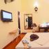 A25 Hotel Mai Hac De room in Hanoi with bed, wall-mounted TV, desk, mirror, and orange curtains.