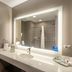 The Mosey Buffalo Williamsville bathroom vanity with lit mirror, sink, toilet, and shower