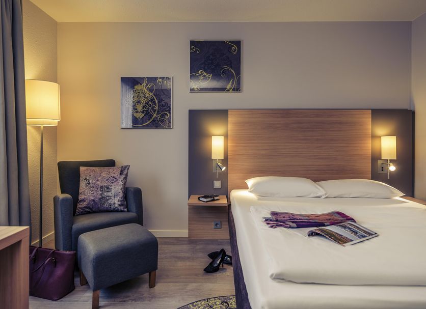 Fürther Hotel Mercure Nürnberg West guest room with double bed, armchair and floor lamp in Fürth