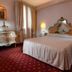 Ca Rialto House Venice hotel room with ornate bed, bedside lamps, curtains and red patterned carpet