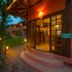 Pousada Villa Da Prainha in Ilhabela with lit entrance, garden path and rustic wooden exterior at dusk