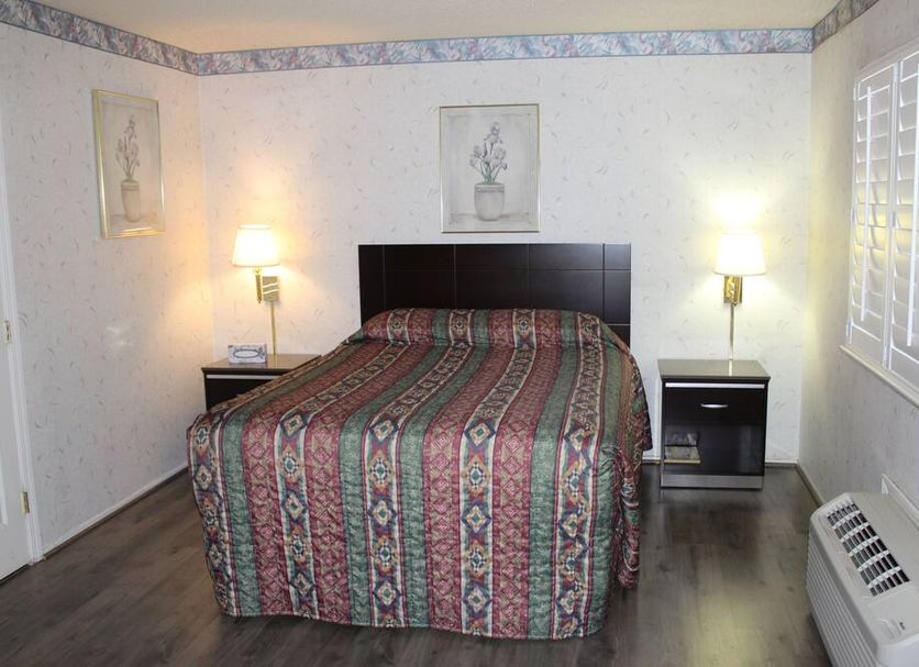 Budget Inn Redwood City guest room with a bed, bedside lamps, and window shutters