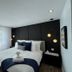 Domaine Belle Plage guest room in Baie-Saint-Paul with king bed, black accent wall and sheer curtains