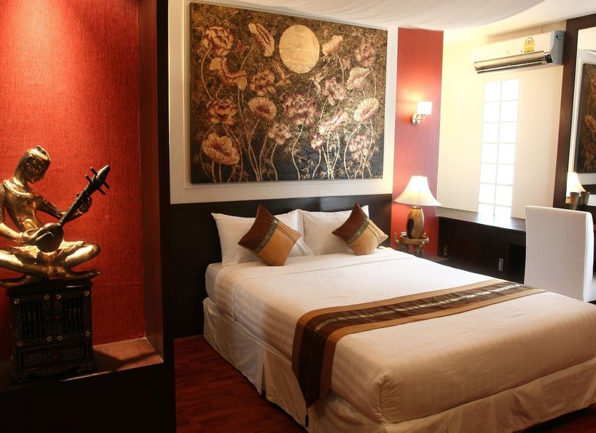 Mirth Sathorn Hotel in Bangkok guest room with double bed, wall art, and gold Buddha statue
