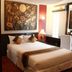 Mirth Sathorn Hotel in Bangkok guest room with double bed, wall art, and gold Buddha statue