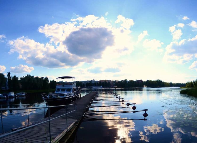 Original Sokos Hotel Vaakuna in Hämeenlinna with a lakeside pier and docked boat at sunset